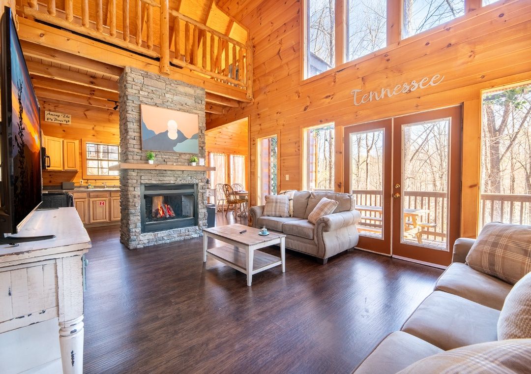 Living room with fireplace, tall wood ceiling, and cabin seating