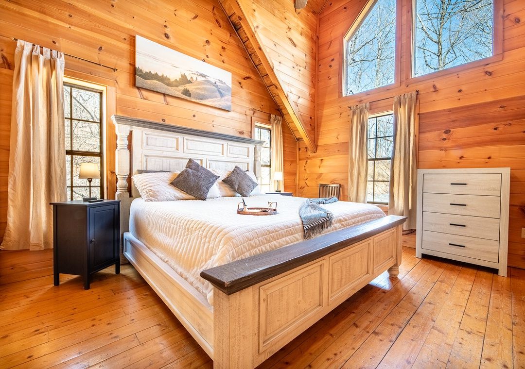 Primary bedroom with cabin wood walls and mountain decor